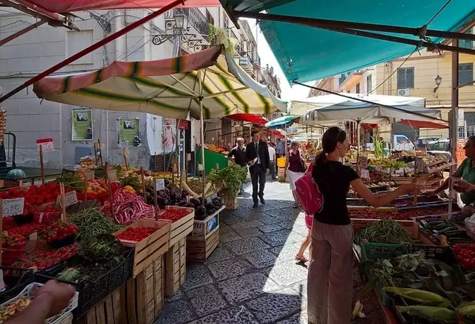 A woman stands at a stall in a market in Palermo